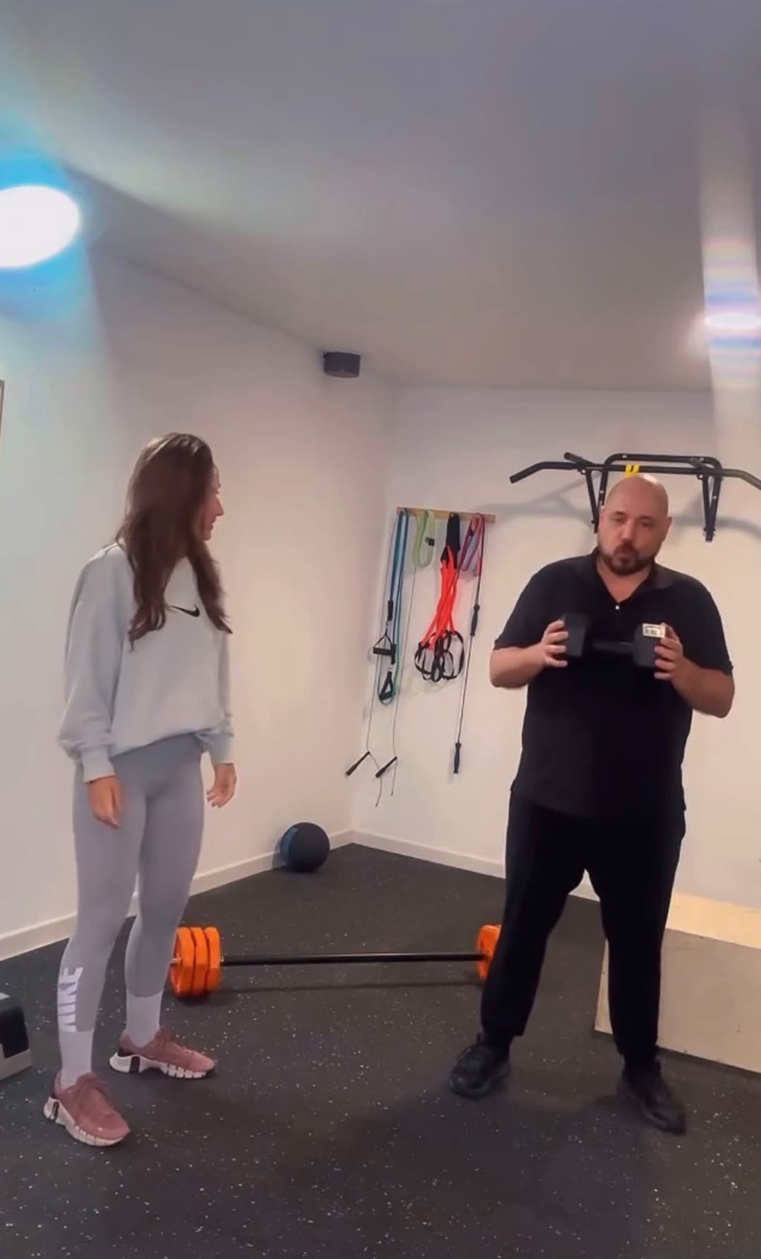 Sesión de entrenamiento personal en la sala: explicación de un ejercicio con mancuerna