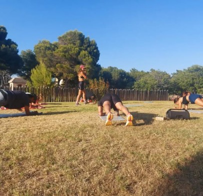 Entrenamiento en grupo reducido al aire libre: varias personas haciendo plancha sobre el césped